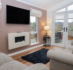 A living room with a television and fireplace at High Lake View Lodge White Cross Bay near Troutbeck Bridge