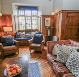 A living room with sofa, armchairs, and a table at Ostlers, Burford