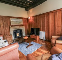 A living room with a fireplace and sofa at Ostlers in Burford