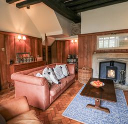 A living room with a sofa, coffee table, and fireplace at Ostlers in Burford