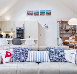 A living room with a sofa and kitchen in Beachcombers Marhamchurch