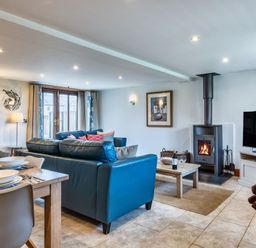 A living room with a sofa and a wood stove at Woodyplatt in Marhamchurch