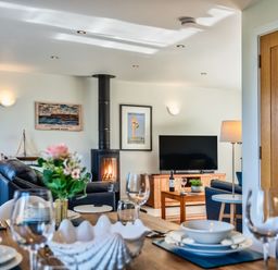 A living room with a television, sofa, and dining table at Chapel Park in Marhamchurch