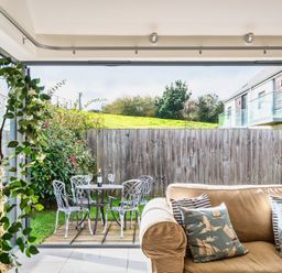 A living room with a view of an outdoor seating area at Little Main in Marhamchurch
