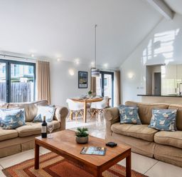 A living room with sofa and dining area at Little Main in Marhamchurch