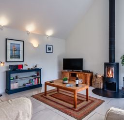 A living room with a sofa, coffee table, and fireplace at Little Main in Marhamchurch