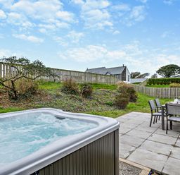 An outdoor area with a hot tub and dining set at Long Down Spa in Marhamchurch