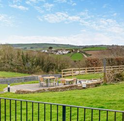 An outdoor seating area with a table and chairs at Middle Hill in Marhamchurch