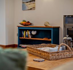 A living room with a basket and bookshelves at Middle Hill Marhamchurch