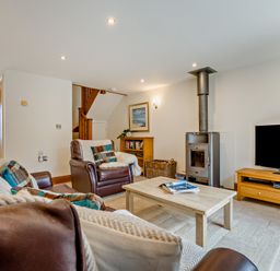 A living room with a sofa, armchair, and television at Sand Parks in Marhamchurch