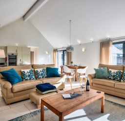 A living room with a sofa and dining table at Warrens Spa in Marhamchurch
