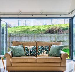 A snug with a sofa and large open doors at Warrens Spa Marhamchurch