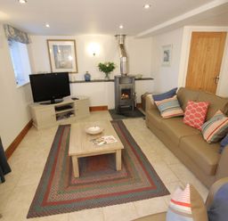 A living room with a television and a wood stove at Westcotts in Marhamchurch