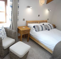A bedroom with a bed and chairs at Westcotts in Marhamchurch
