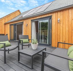 An outdoor patio with chairs and a table at Gwari Spa Barn 2.0 Marhamchurch