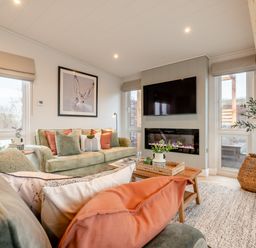 A living room with a sofa, coffee table, and television at Trelowen 2.0 Spa in Marhamchurch