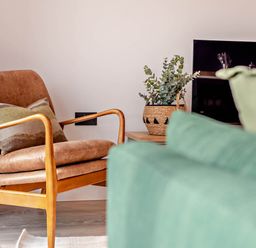 A living room with an armchair and a plant at Arvor Duplex 2.0 in Marhamchurch