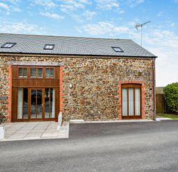 A stone building with windows and doors at Jack's House in Marhamchurch