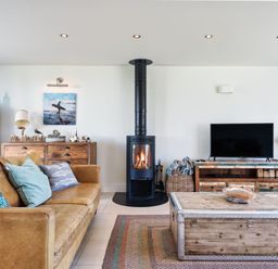A living room with a fireplace and sofa at Eagle's Nest in Marhamchurch