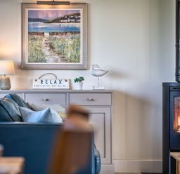 A living room with a sofa and a wood stove at Trevelyan in Marhamchurch