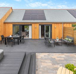 An outdoor area with decking, a table, chairs, and a spa at Gwari Spa Barn 3.0 in Marhamchurch