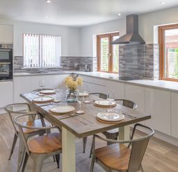 A kitchen with a dining table and chairs at Windy Hills Spa in Marhamchurch