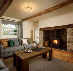 A living room with a sofa and fireplace at Whalesborough Farmhouse Spa in Marhamchurch