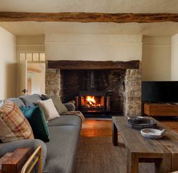 A living room with a fireplace and sofa at Whalesborough Farmhouse Spa Marhamchurch