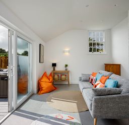 A living room with a sofa and cushions at Whalesborough Cottage Spa in Marhamchurch