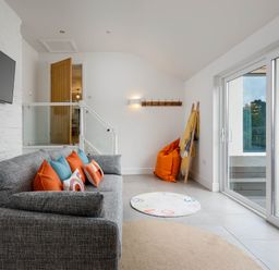 A living room with a sofa and a television at Whalesborough Cottage Spa in Marhamchurch