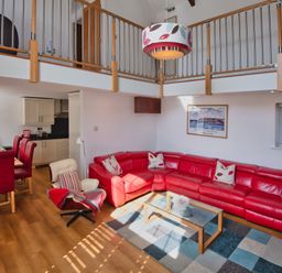 A living room with a red sofa and dining area at Calf House Spa in Marhamchurch