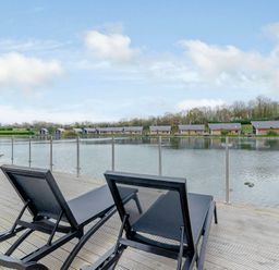 An outdoor area with sun loungers overlooking a lake at Tranquillity 4 (Pet) in Carnforth