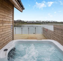 A hot tub on a wooden deck overlooking water at Tranquillity 4 (Pet) in Carnforth