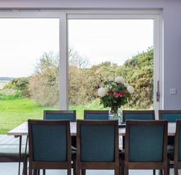 A dining room with a table and chairs overlooking a green outdoor area at The Laidlaw in North Berwick