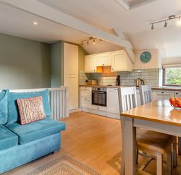 A living room and kitchen with a sofa and dining table at Crabtree Cottage in Bude