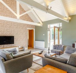 A living room with a television, sofas, and coffee table at Godolphin Stable in Bude