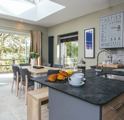 A kitchen with a table and chairs, coffee and croissants at Cornish Lodge Spa in Bude