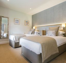 A bedroom with two beds and a mirror at Cornish Lodge Spa in Bude