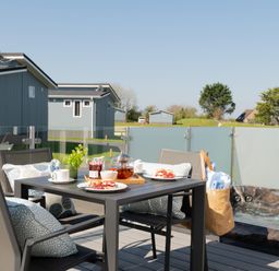 An outdoor dining area with a table and chairs at Kynance Spa (Pet) Bude