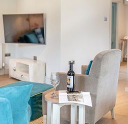 A living room with a chair and table at Summerleaze Garden Cottage 3 Spa in Bude