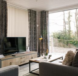 A living room with a television and sofa at The Glasshouse in Bude