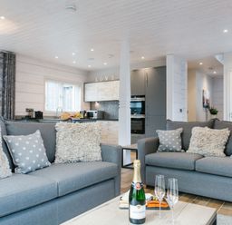 A living room with sofas and a kitchen in the background at The Glasshouse in Bude