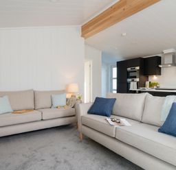 A living room with couches and a kitchen area at Mullion Spa (Pet) Bude