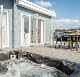 An outdoor area with a hot tub and dining table at Sennen 3 Spa (Pet) in Bude