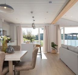 A living room with a dining area and kitchen cabinets at Sennen 3 Spa (Pet) in Bude