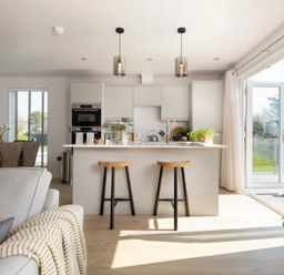A kitchen with an island and stools at Sennen 3 Spa (Pet) Bude