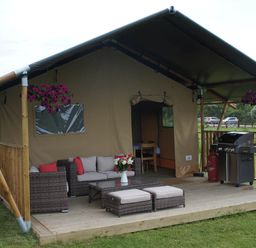 An outdoor seating area with a tent, sofa, table, and barbecue grill at Standard Safari Tent in Fair Oak