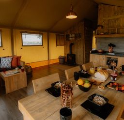 A dining area with wooden furniture and kitchenette in Deluxe Safari Tent Fair Oak