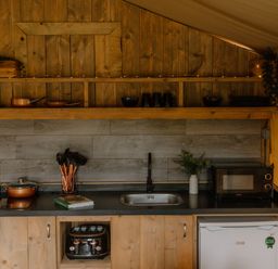 A kitchen with a sink, microwave, and storage at Deluxe Safari Tent in Fair Oak