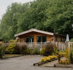 An outdoor view of a wooden lodge surrounded by greenery at Spitfire Lodge in Fair Oak
